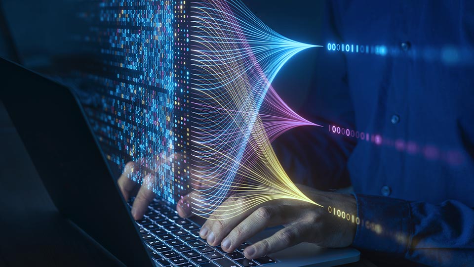 Hands typing on a laptop with colorful data streams.