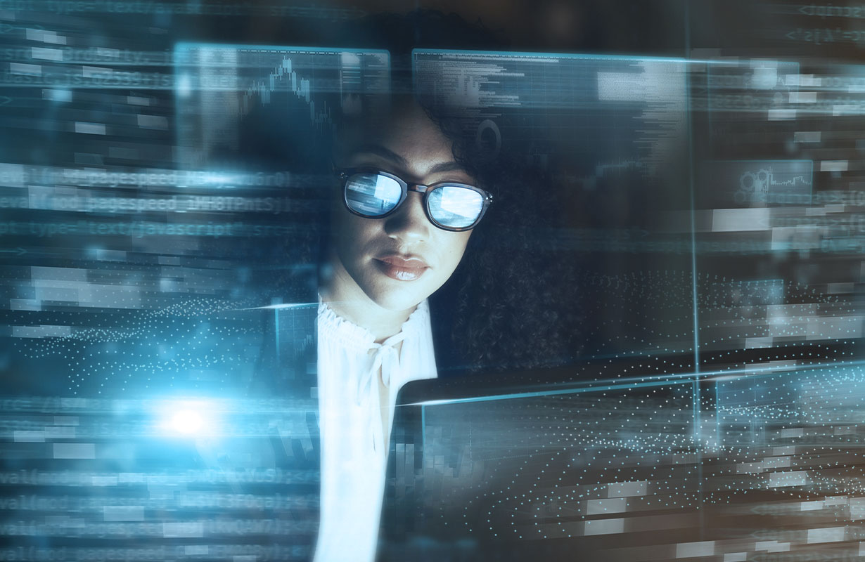 Person wearing glasses analyzing floating digital data and graphs on transparent screens in a dark tech environment.