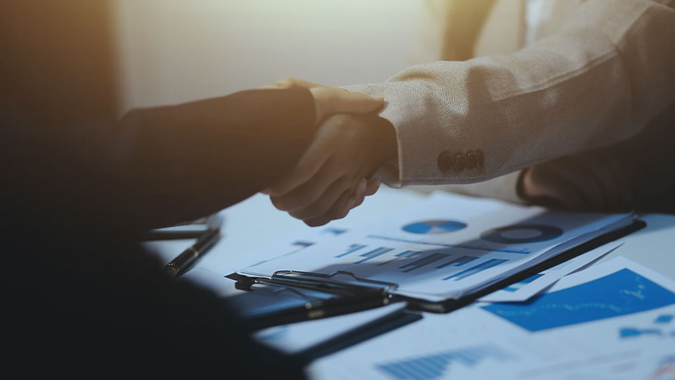 Business professionals shaking hands over a meeting table.