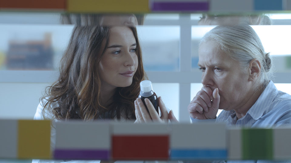 Healthcare professional helping a patient with their cough medication.