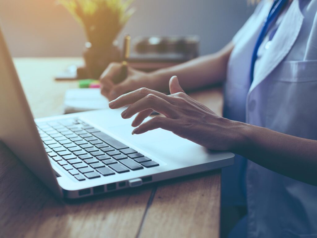 Close-up of a person using a laptop at a desk.