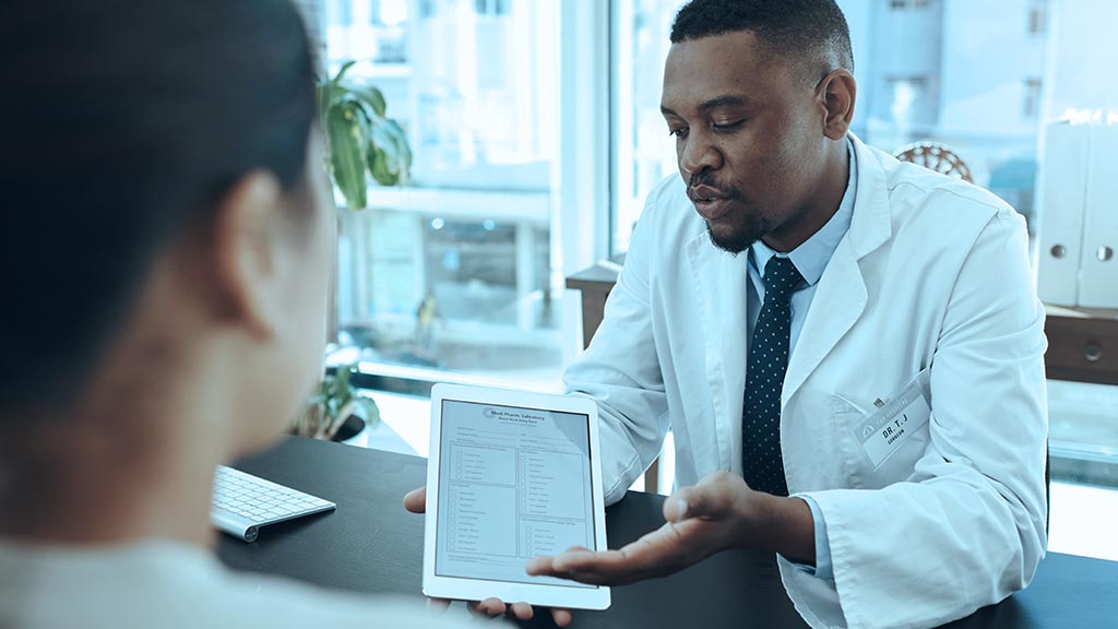 A focused doctor in a white coat explains a medical report on a tablet to a patient during consultation in a clinic.