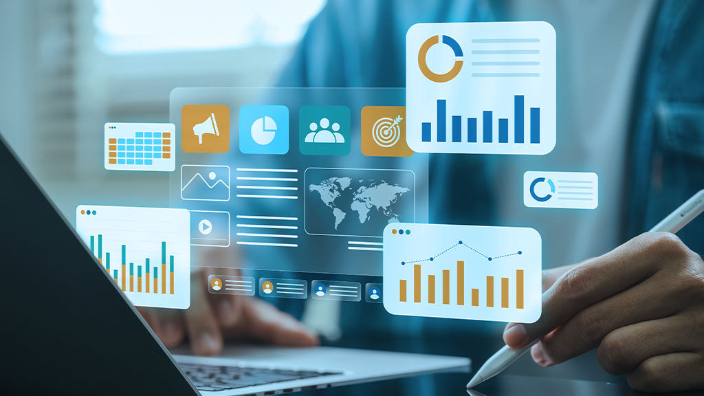 Digital business analytics dashboard with charts, global map, marketing icons, and a person using a stylus beside a laptop.