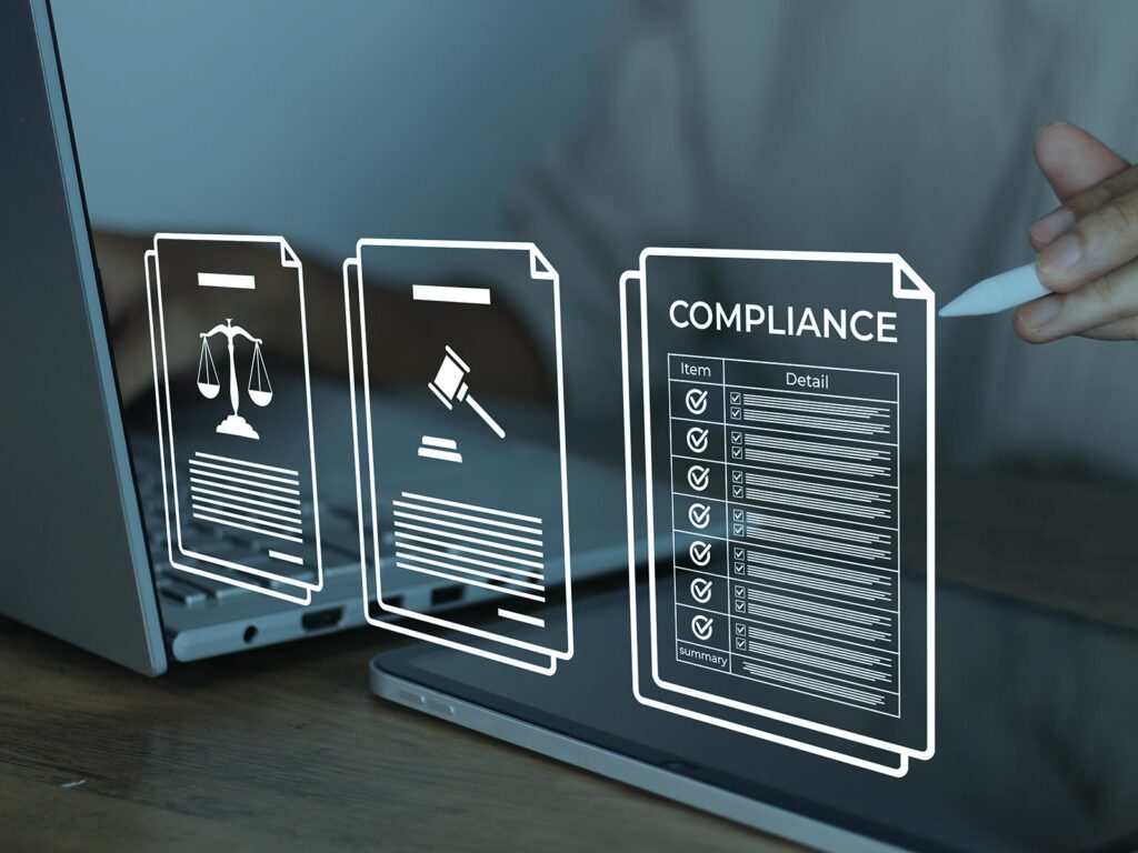 Digital compliance documents with legal icons and checklist displayed on screens, while a hand points with a stylus.